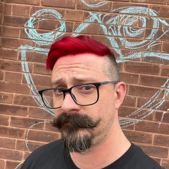 Picture of Geoff with red hair in front of brick wall